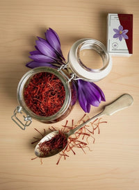 Saffron threads in a glass preserving jar with fresh purple crocus flowers and a vintage spoon